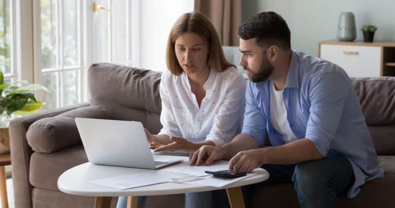 A couple reviewing finances using a laptop, calculator, and paperwork