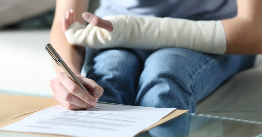 A person who has an arm injury on one arm and using the other hand to fill out paperwork