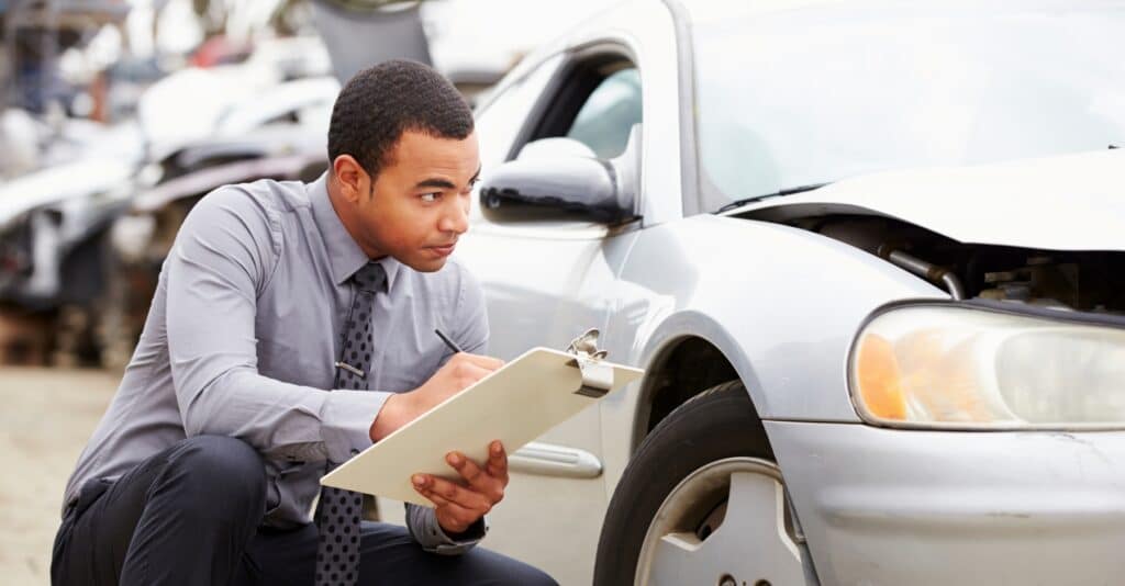 An insurance representative or estimator reviewing a car that has been in an accident